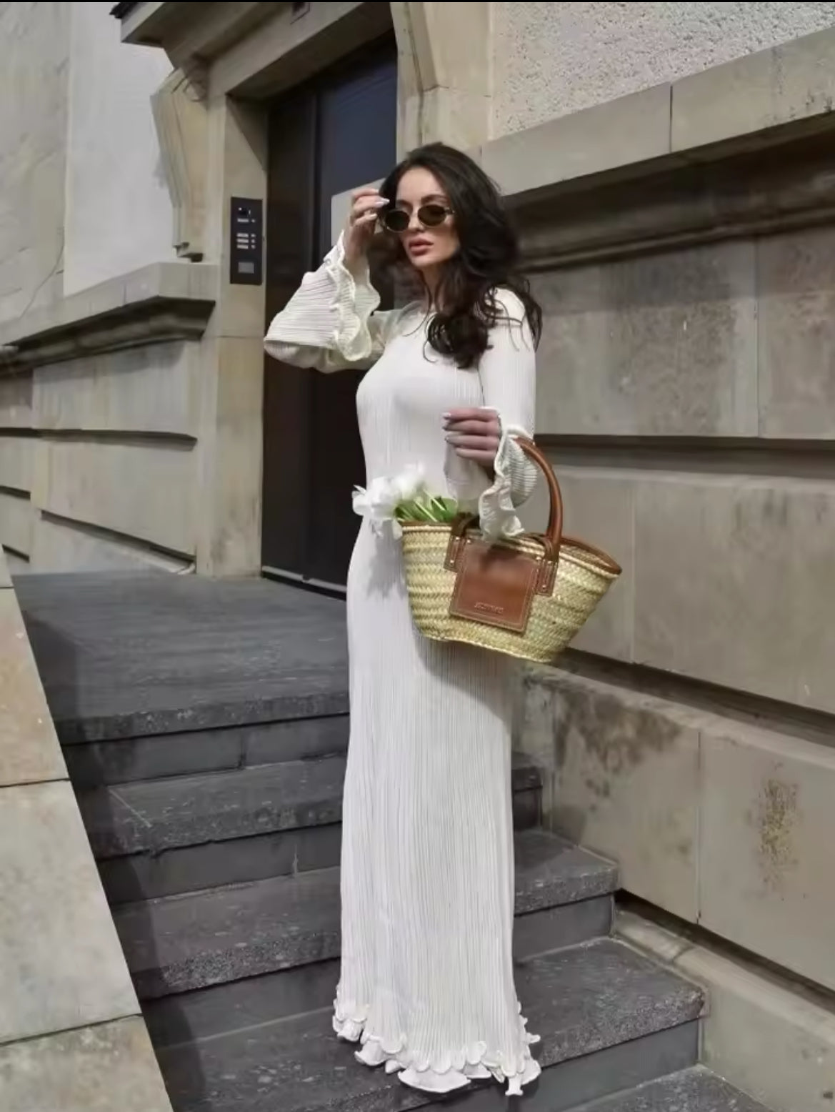Elegantes Maxikleid in Cremeweiß mit verspieltem Rückendetail und Schnürung. Weit geschnittene Ärmel und wellenförmige Säume für einen romantischen, femininen Look. Kombiniert mit einer edlen Strohtasche – perfekt für stilvolle Sommer- und Frühlings-Outfits.
