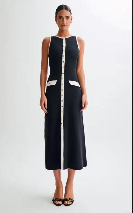Schwarzes Midikleid mit kontrastierenden weißen Details und goldenen Knöpfen. Zeitlos-elegantes Design mit taillierter Silhouette für einen modernen und klassischen Look. Perfekt für Business und besondere Anlässe.