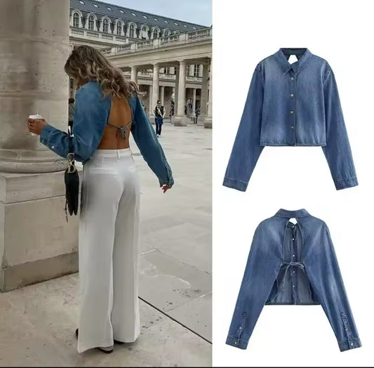 Modische cropped Jeansbluse mit langen Ärmeln, vorne geschlossen mit Knopfleiste, hinten komplett rückenfrei mit Bindeband – getragen mit weißer High-Waist-Hose im Pariser Innenhof.