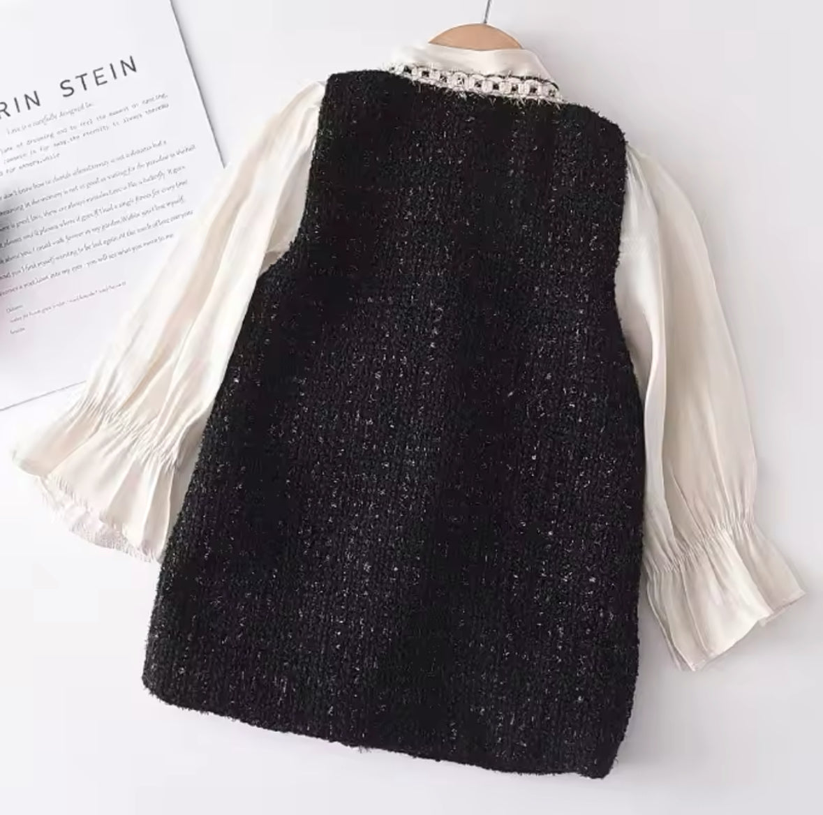 Mädchen-Tweed-Kleid in Schwarz mit Perlenknöpfen, dekorativen Taschen und cremefarbener Bluse mit Schleife und langen Ärmeln.