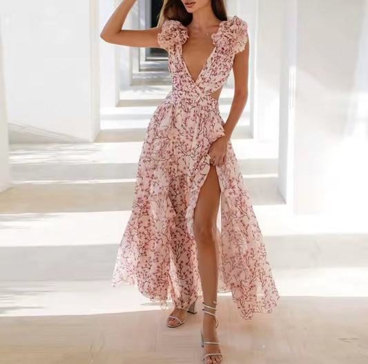 Modell trägt ein elegantes Maxikleid mit Rüschenärmeln, tiefem Ausschnitt, floraler Musterung und Cut-outs an der Taille.