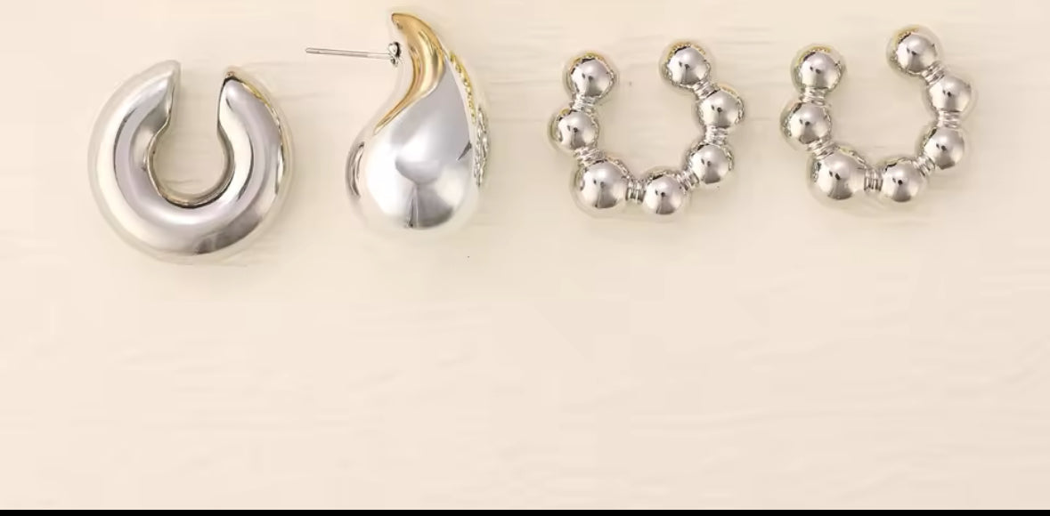 Nahaufnahme eines futuristischen Ear-Cuff-Ohrrings in glänzendem Silber. Das Design besteht aus mehreren Kugel- und Tropfen-Elementen, die kunstvoll das gesamte Ohr umschließen. Die hochglänzende Oberfläche reflektiert das Licht und sorgt für einen modernen, avantgardistischen Stil.