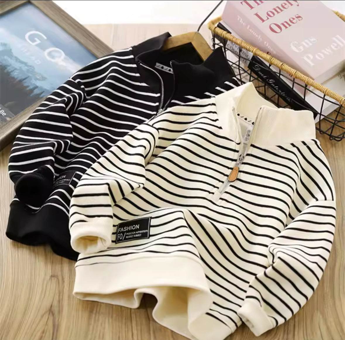 Zwei gestreifte Kinder-Sweater mit Half-Zip in Schwarz-Weiß und Creme-Schwarz.