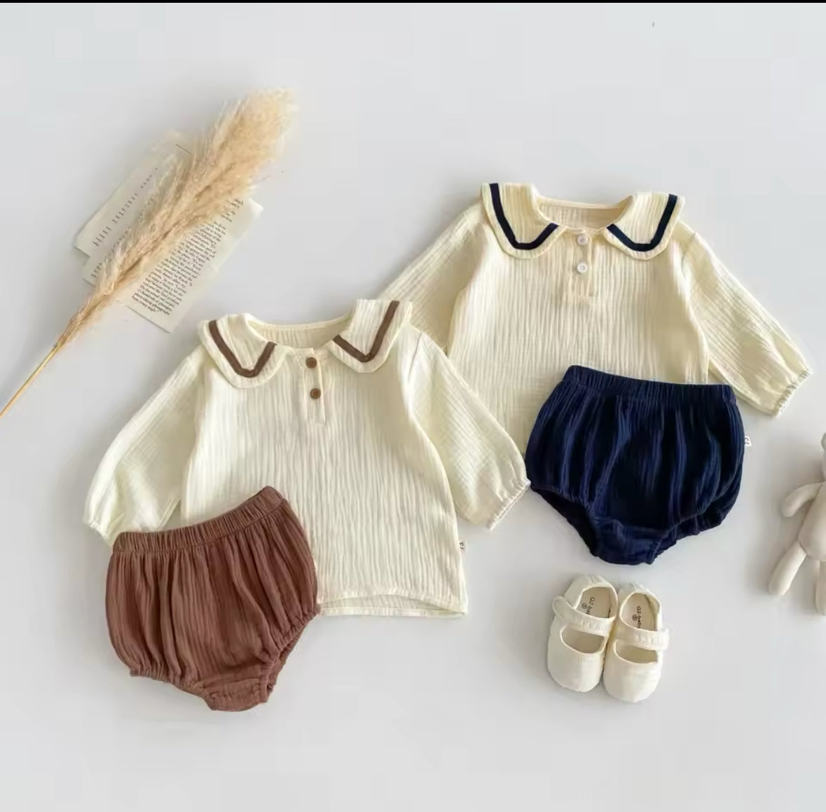 Zwei Baby-Zweiteiler in Beige mit braunen & blauen Details, inklusive Shorts.