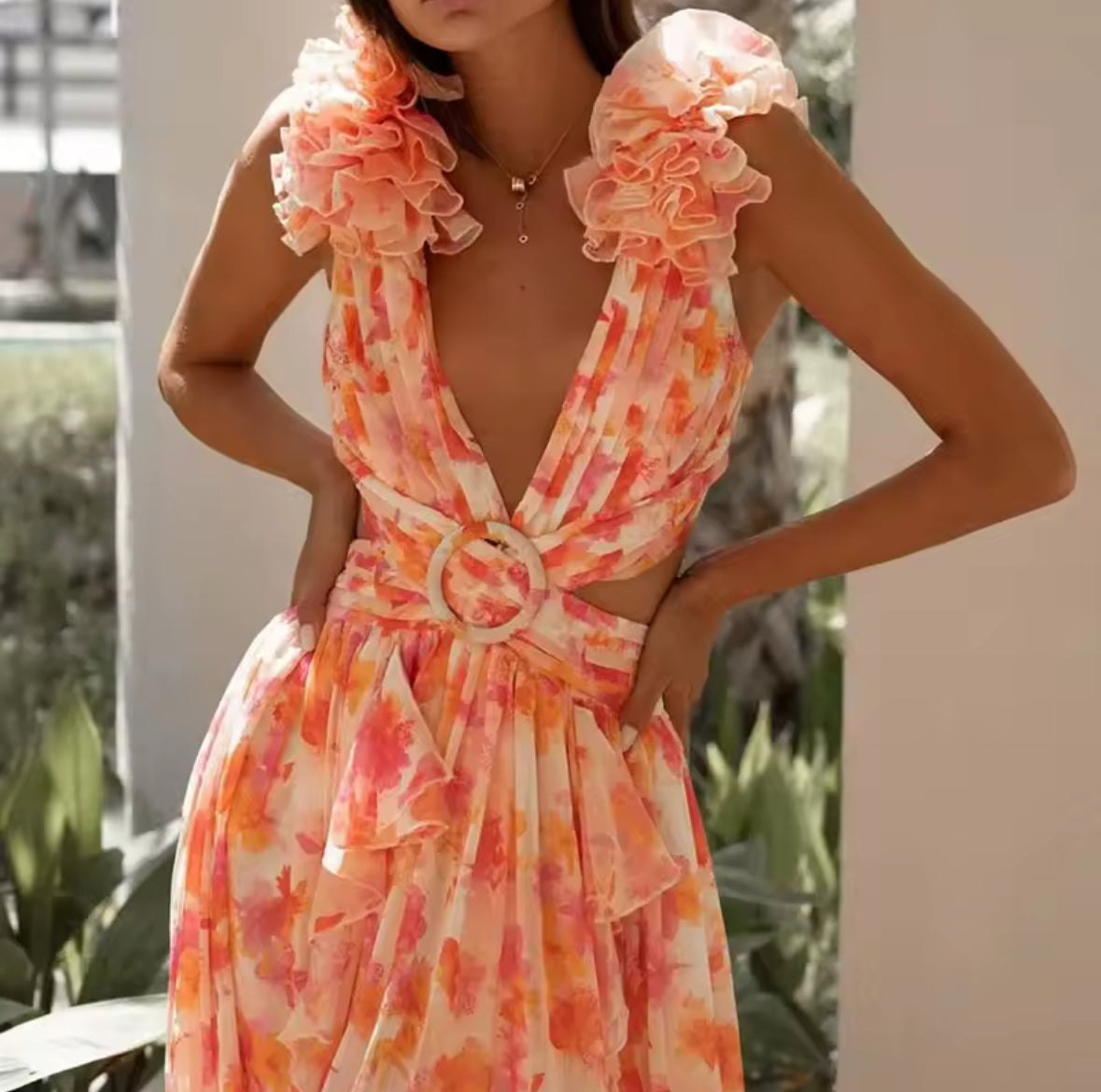 Modell trägt ein elegantes Maxikleid mit Rüschenärmeln, tiefem Ausschnitt, floraler Musterung und Cut-outs an der Taille.