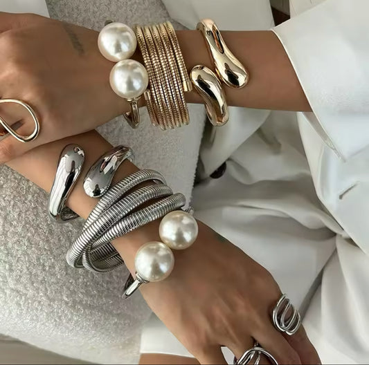 Luxuriöses Armreif-Set in Gold mit strukturierten Armreifen, glänzend geschwungener Armspange und offenem Armreif mit zwei großen Perlen – elegantes Statement-Schmuckstück

Elegantes Armreif-Set in Silber mit mehreren strukturierten Armreifen, offener Spange mit Perlen und glänzend geformtem Armreif – moderner, minimalistischer Statement-Schmuck.