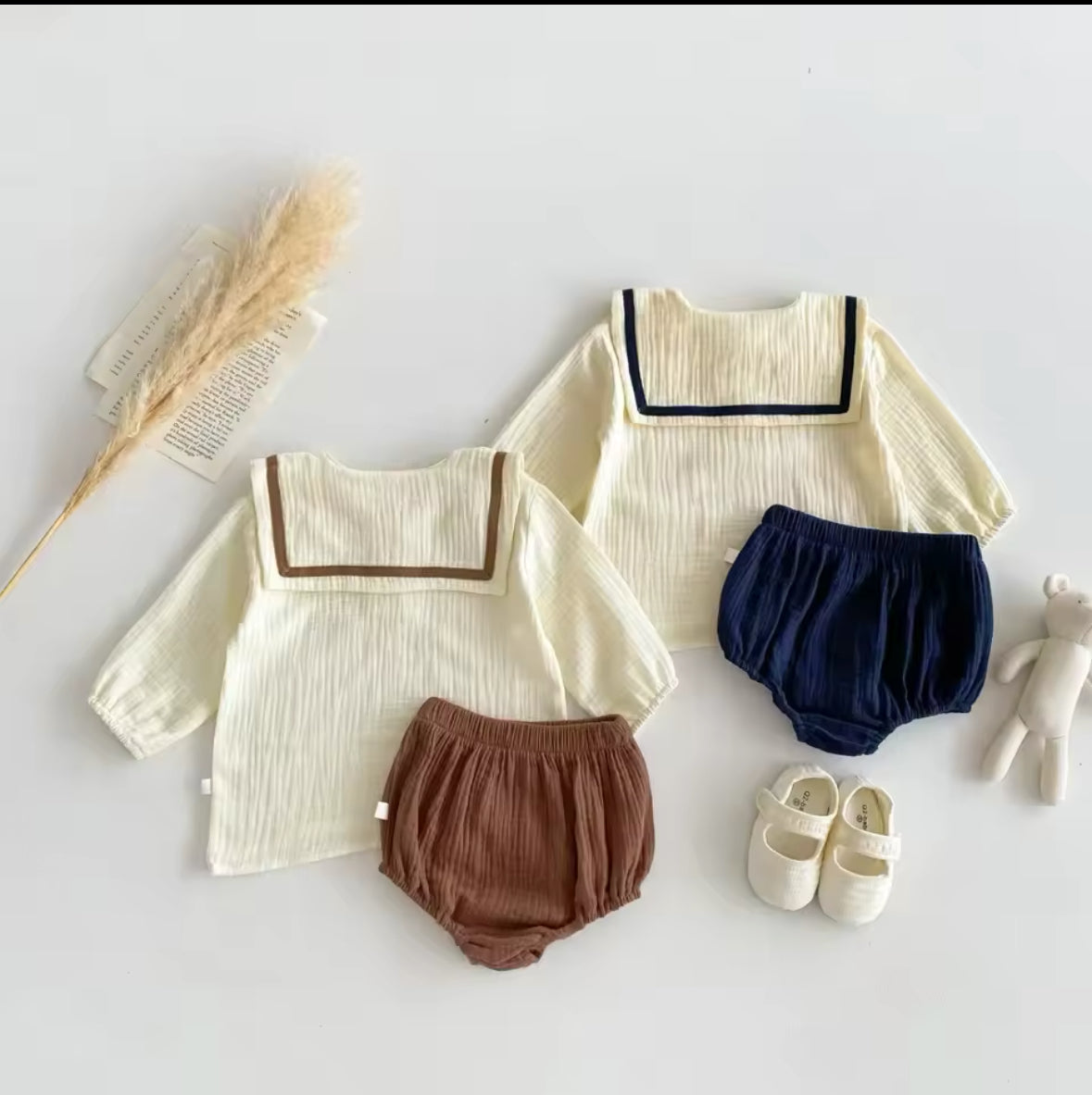 Niedliches Baby-Set mit Vintage-Kragen in Beige & Marineblau, dekorativ aufgehängt.