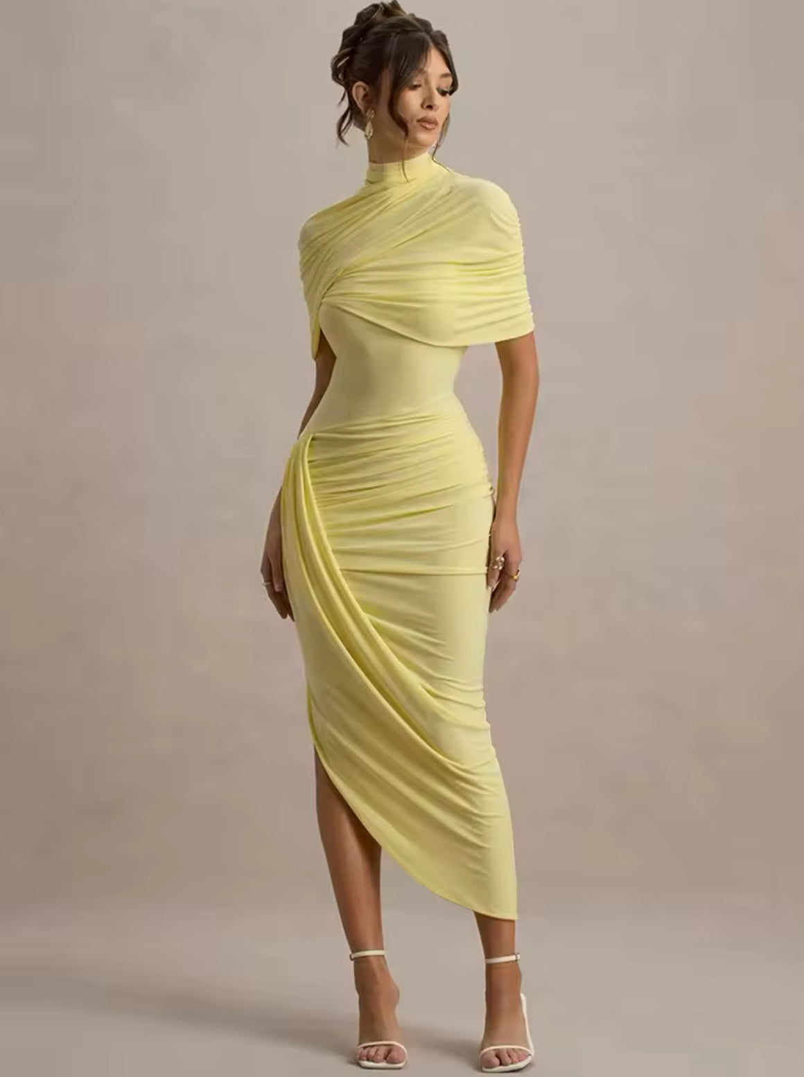 Alt-Text: Modell trägt ein pastellgelbes, eng anliegendes Midikleid mit kunstvollen Drapierungen, hohem Kragen und asymmetrischem Saum.